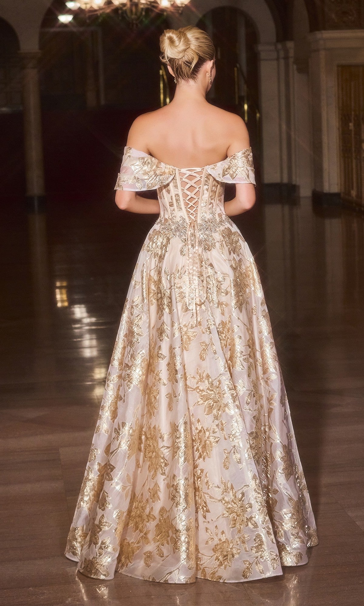 A blonde woman in an updo wears the Ladivine CD682 long prom dress—an off-the-shoulder, floor-length gown with metallic floral jacquard and a lace-up back—standing in an ornate hall.